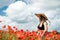 portrait of rpetty ukrainian woman in black top and hat with big bouquet of poppies in field