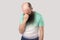 Portrait of sad alone depressed middle aged bald man with long beard in light green t-shirt standing holding his head down and