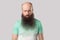 Portrait of sad alone middle aged bald man with long beard in light green t-shirt standing, frowning and looking at camera with