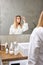 Portrait Of Sad Blonde Female Worried About Hair, Looking At Mirror In Bathroom