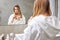 Portrait Of Sad Blonde Female Worried About Hair, Looking At Mirror In Bathroom