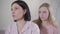 Portrait of sad Caucasian woman looking away as her teen blond daughter touching her shoulder. Blurred upset girl making