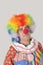 Portrait of sad senior male clown against colored background