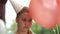 Portrait of sad teenage fair-haired girl in birthday hat with balloons in hands. Lonely birthday concept