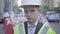 Portrait of sad tired little boy in constructor helmet on his head, and uniform looking away. Architect concept