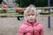 Portrait of sad upset Caucasian girl on closed playground outdoor. Kids play area locked with yellow caution tape in Toronto city