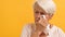 Portrait of sad vulnerable old woman wiping her tears. Isolated on the orange background