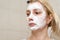 A portrait of a sad woman with problem acne skin making a cleansing purifying white facial mask, anti black spot and acne