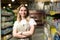 Portrait of saleswoman, woman smiling and looking at camera in supermarket. Pleasant friendly female seller standing in the store