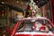 Portrait of santa claus driving a car loaded with a Christmas tree and gifts