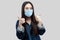 Portrait of satisfied beautiful asian young woman with surgical medical mask in blue jacket standing, thumbs up, smiling and