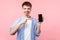 Portrait of satisfied mobile user, happy brown-haired man pointing at phone and smiling. isolated on pink background