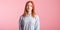 Portrait of a satisfied redhead girl in the studio on a pink background.