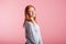 Portrait of a satisfied redhead girl in the studio on a pink background.