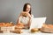 Portrait of satisfied smiling woman watching films or funny video laptop computer, eating tasty hamburger, wearing white t-shirt,