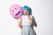 Portrait of scared asian girl in halloween costume and blue wig, gasping and looking ambushed, holding balloon with