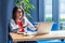 Portrait of scared beautiful stylish brunette young woman in glasses sitting, looking and reading some news at her laptop screen