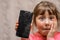 Portrait of a scared little girl with a broken mobile phone. A sad child broke the screen of a mobile phone. Cracked display in