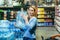 Portrait of scared woman shopper in supermarket buying water in plastic bottles