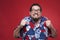 Portrait of a scared young man in Hawaiian shirt against red background.