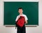 Portrait of a school boy looking for school supplies in his backpack, blackboard background - back to school and education concept