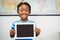 Portrait of schoolboy showing digital tablet in classroom