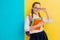 Portrait of a schoolgirl in glasses with books textbooks on a yellow blue background in the Studio.