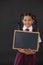 Portrait of schoolgirl holding blank slate against blackboard