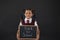 Portrait of schoolgirl holding slate with text against blackboard