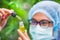 Portrait of scientist with mask, glasses and gloves researching and examining hemp oil in a greenhouse. Concept of herbal