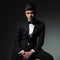 Portrait of seated elegant man in black tuxedo