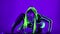 Portrait of seductive flexible woman in futuristic costume with fluorescent makeup setting music on DJ set looking at