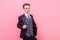 Portrait of self-confident magician in tuxedo looking at camera with arrogant sarcastic smile. studio shot  on pink