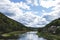 A portrait of the semois river with on one side a small village and on the other a forest and a mountain