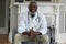 Portrait of senior african american male doctor giving patient consultation at home