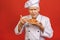 A portrait of a senior baker holding croissant isolated on red background