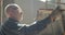 Portrait of senior carpenter checks the quality of a wooden board in manufacture.