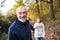 A portrait of a senior couple walking in an autumn nature.