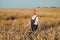 Portrait of senior farmer agronomist in wheat field checking crops before harvest. Successful organic food production and