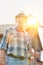 Portrait of senior farmer holding fork rake against barn