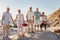 Portrait Of Senior Friends Standing On Rocks By Sea On Summer Group Vacation