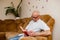 Portrait of a senior handsome wise man sitting on a sofa in a room and reading an academic book. Smiling mature 60s