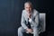 Portrait of senior lawyer on chair with smile, confidence and mockup space on dark background in studio. Pride