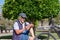 Portrait of senior man with electro bike sitting outdoors in the park using mobile phone. Smiling elderly grandfather wearing