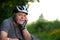 Portrait of senior man enjoying summer cycling in the forest during lovely sunset, active pensioner