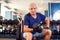 A portrait of senior man in the gym training with dumbbells. People, health and lifestyle concept