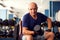 A portrait of senior man in the gym training with dumbbells. People, health and lifestyle concept