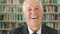 Portrait of a senior man laughing and smiling while standing in a library. Face of a mature lecturer looking cheerful