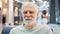 Portrait of senior man sitting in mall looking at camera. Male shopper in shopping center, smiling