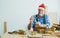 Portrait senior old aging kind Caucasian man or carpenter wearing santa hat, making DIY wooden furniture, holding eyeglasses,